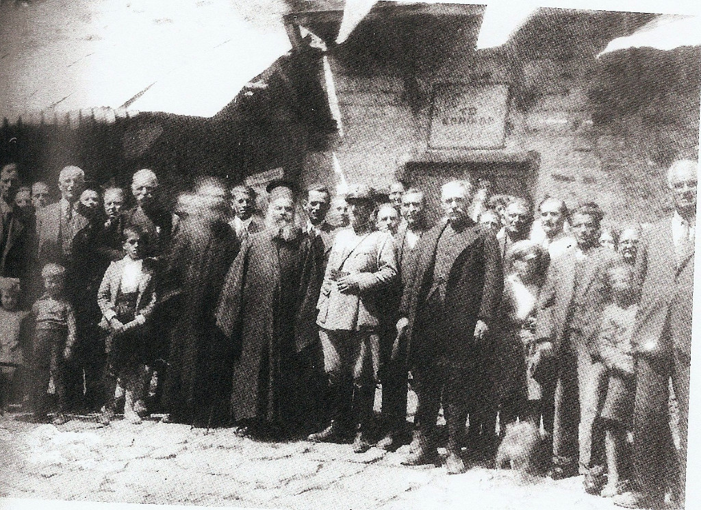4 Αυγούστου 1936, πρώτη επέτειος καθεστώτος Μεταξά, στο Σέλι για πρώτη φορά εορτάζεται ένα γεγονός τόσο πανηγυρικά, μετά τη δοξολογία ακολούθησε παρέλαση και εορταστικός λόγος από τον υπεύθυνο του κόμματος. Φωτογραφία μπροστά από το καφενείο “Το Εθνικόν”, διακρίνονται οι , παπά-Κολιπέτρης (βλάχος), παπά-Ποζιάδης (αμυδρά), στρατιωτικός εκπρόσωπος Γ. Τρυγώνης.